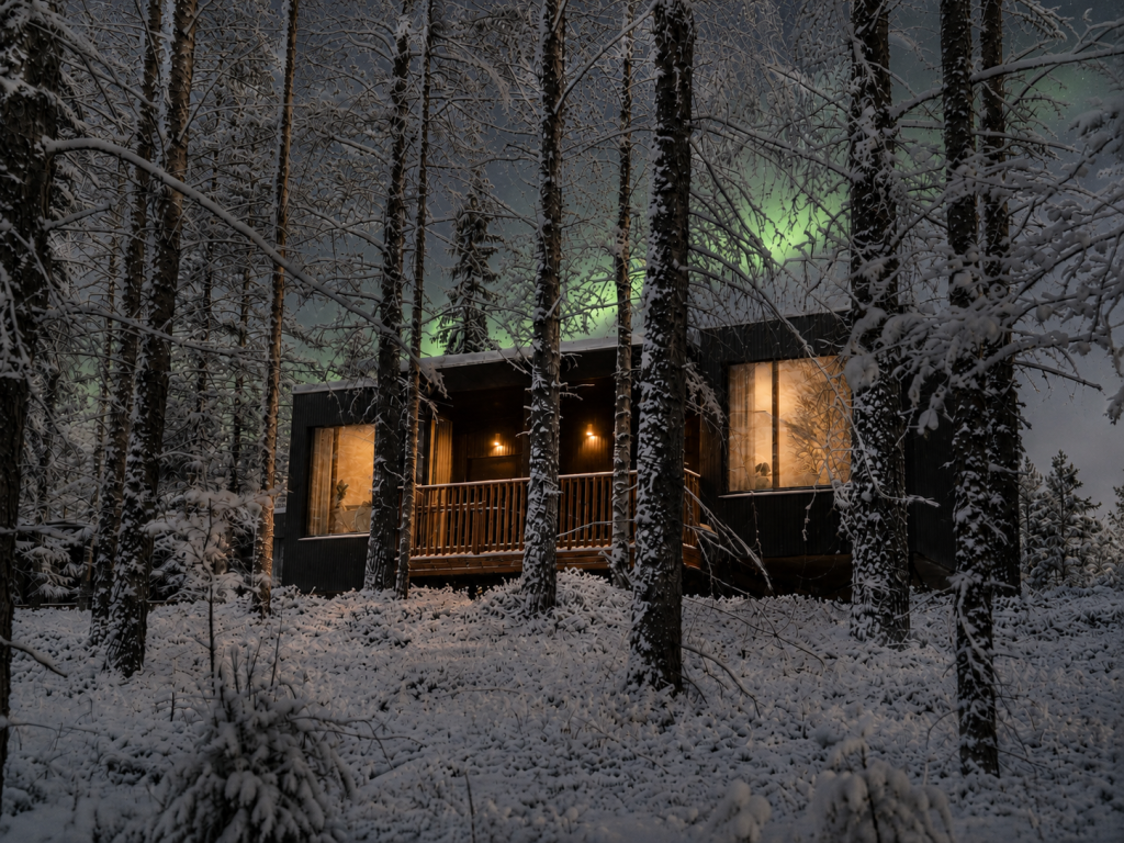 Deluxe Villa exterior surrounded by snow-covered pine trees in Finnish Lapland.